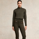 Woman wearing an olive green equestrian outfit on a beige background