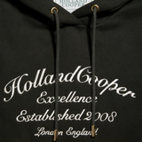 Dark green hoodie with 'Holland Cooper' branding and text on a blurred background