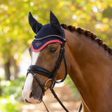 Horse wearing a black and cranberry red ear bonnet with blurred trees in the background