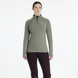 Person wearing a green long-sleeve riding top with a brand logo on a white background