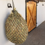 Hay net hanging from a hook in a stable setting