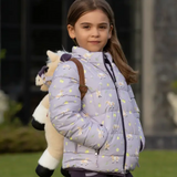 Young girl wearing a light purple puffer jacket with animal patterns, holding a plush toy, outdoors.