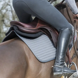 Close-up of a horse rider and a brown leather saddle in an outdoor setting