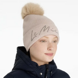 Beige knit beanie with pom-pom worn by a person on a white background
