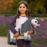 Young girl holding a toy horse in front of a blurred lavender field