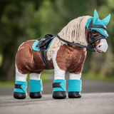 Plush toy horse with turquoise details on a blurred natural background