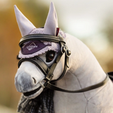 Close-up of a horse wearing a bridle with a visible brand logo against a blurred natural background