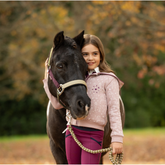 LeMieux AW26 Medley Headcollar Variant Colour Gooseberry/Pear/Petal. A dark coloured pony with a young person holding horse head. Horse is wearing gooseberry headcollar with matching lead rope and person with wearing pink top on faded autumn background.