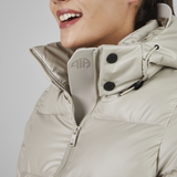 Close-up of a person wearing a beige puffer jacket with a brand logo on a light grey background