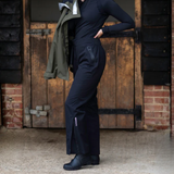 Person wearing black rain gear standing in front of a wooden door.