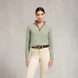 Holland Cooper Country Quarter Zip Knit Variant Colour Sage. A model wearing a sage green sweater, brown belt and cream trousers on grey background.