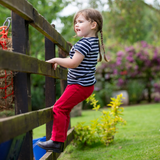 Little girl wears the Shires Childrens Winnie & Me Jodhpurs whilst climbing a fence