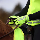 Person wearing bright yellow gloves and a reflective vest interacting with a horse.