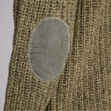 Close-up of a green knitted garment with an elbow patch on a grey background