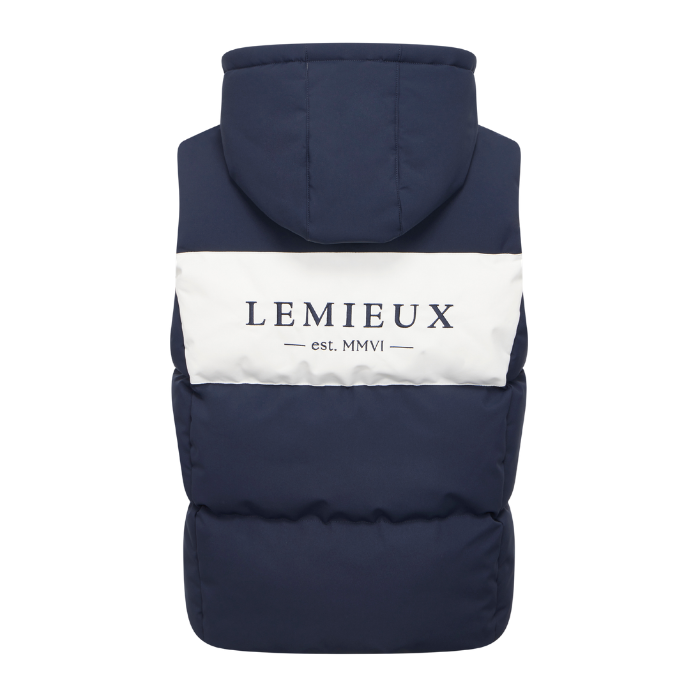 LeMieux AW26 Young Rider Joey Hooded Gilet Varient Navy. A navy blue hooded puffer vest shown from the back, featuring a wide white horizontal stripe across the upper back with the brand name 'LEMIEUX est. MMVI' printed in navy.