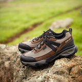 Pair of brown walking boots on a rock with a blurred outdoor background