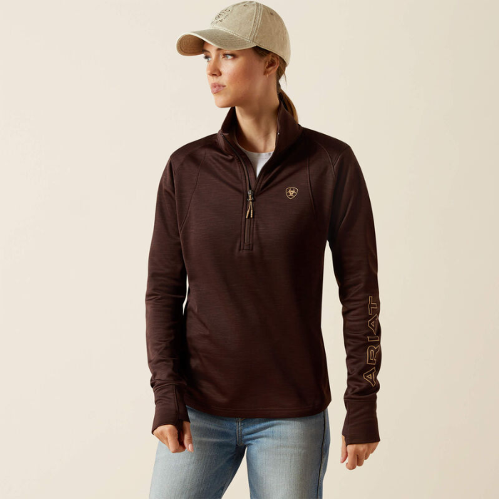 Woman wearing a brown long-sleeve shirt with a logo on a beige background