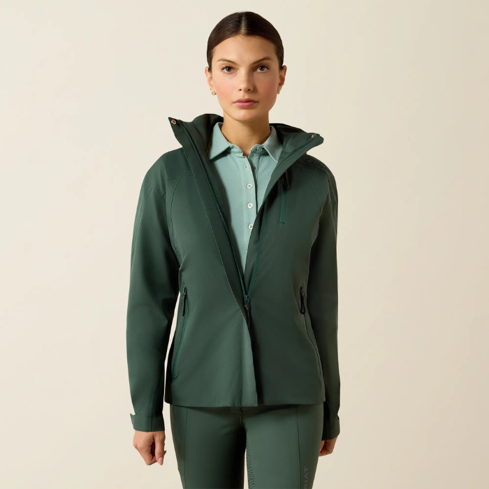 Woman wearing a green jacket over a light blue shirt on a beige background