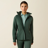 Woman wearing a green jacket over a light blue shirt on a beige background