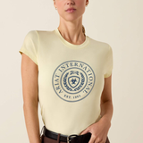 Woman wears a yellow t-shirt with ARIAT INTERNATIONAL logo on a beige background