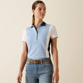 Woman wears a blue and white polo shirt and jeans on a plain background