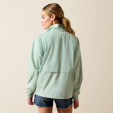 Woman wearing a light green jacket and denim shorts on a beige background