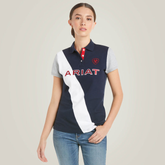 Girl wears a navy polo shirt with white stripe and ARIAT logo on a plain background