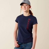 Girl wears navy blue t-shirt with red ARIAT logo on a beige background