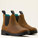 Pair of brown leather boots with black soles on a light beige background