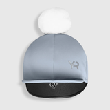 Blue riding hat with white pom-pom and logo on a light grey background