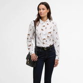 Woman wears a white shirt with dog print detail on a white background