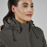 Woman wearing a dark green jacket with a hood against a plain background