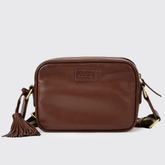 Brown leather crossbody bag with tassel on a light grey background