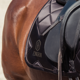Close-up of a horse wearing a black saddle and saddle pad with 'Eskadron' branding.