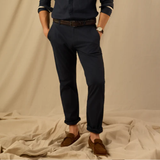 Person wearing navy trousers and brown shoes on a beige background