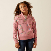 Young girl wearing a pink patterned hoodie against a beige background