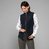 Woman wearing a navy blue gilet over a patterned shirt on a grey background