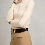 Person wears beige knitted top and beige breeches with brown belt
