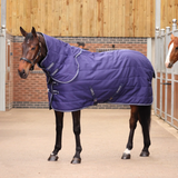 Horse wearing a navy quilted rug in an indoor stable.