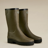 Pair of green rubber boots with black soles on a beige background