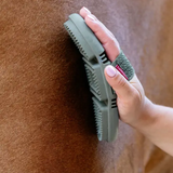 Person using a green brush on a horse's coat