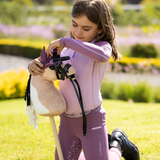 Girl plays with a hobby horse in a grassed area
