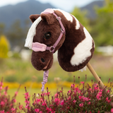 Plush toy horse with a pink headcollar in a field of flowers