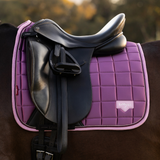 Pink saddle pad under a black dressage saddle on a horse