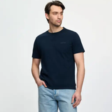 Man wears a navy t-shirt and light jeans on a white background