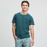 Man wears a green t-shirt and light jeans on a white background