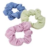 Three hair ties in pink, blue and yellow on a grey background