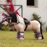 Toy horse wears a pair of pink horse boots in an outdoor setting