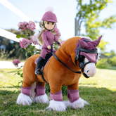 Plush horse with a rider doll in a pink outfit on a grassy field with flowers.