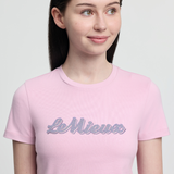 Person wearing a pink t-shirt with 'Le Mieux' text on a light gray background